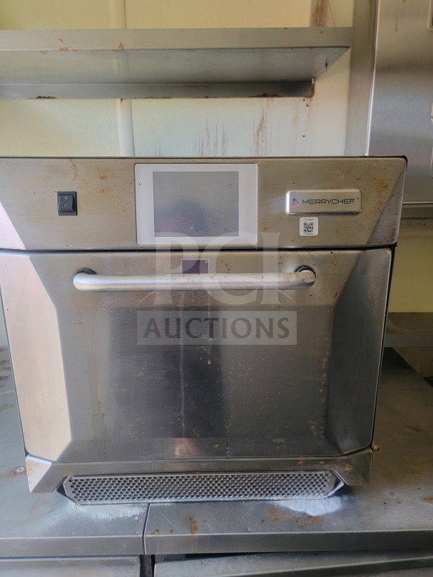 Merrychef commercial oven in used condition, featuring a digital display and metal exterior with visible wear. Tags include model details.