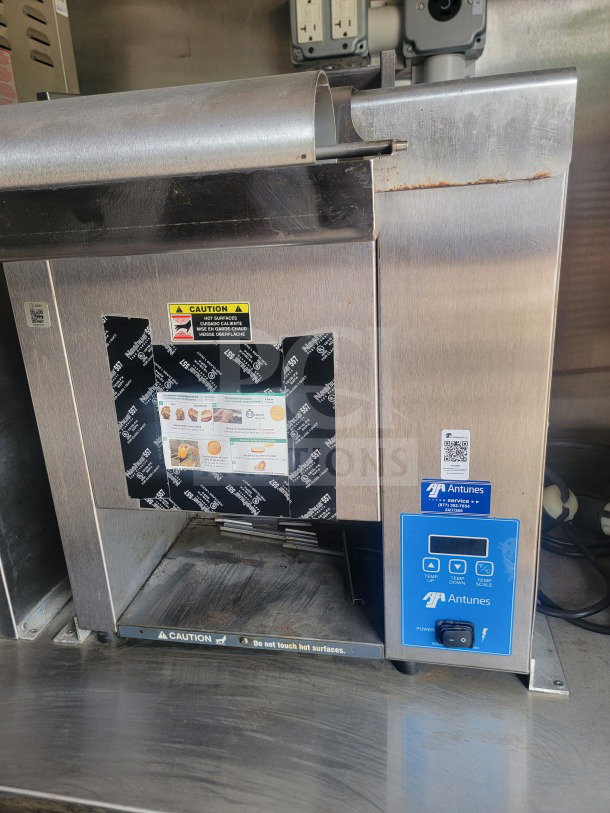 Alt Text: Antunes commercial food warmer inside 2021 Titanium Cargo mobile kitchen trailer; features temperature controls and caution labels.