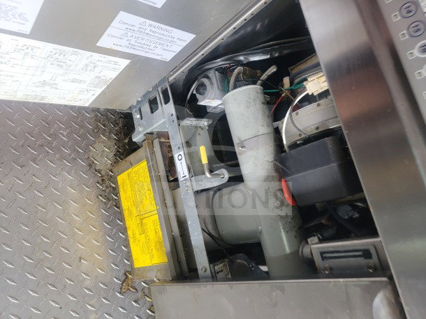 Inside view of a 2021 Titanium Cargo 8.5' x 24' mobile kitchen trailer showing mechanical components and visible warning labels.