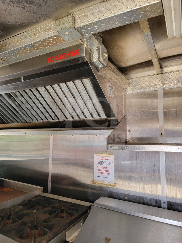 Interior of 2019 Diamond Cargo mobile kitchen trailer, featuring a stove, ventilation hood with "No Smoking" sign, and stainless steel surfaces.