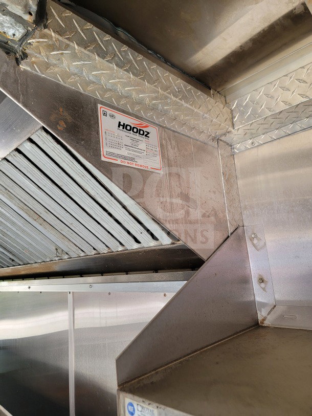 Interior view of a 2019 Diamond Cargo 8.5' x 24' mobile kitchen trailer, featuring a stainless steel HOODZ exhaust system.