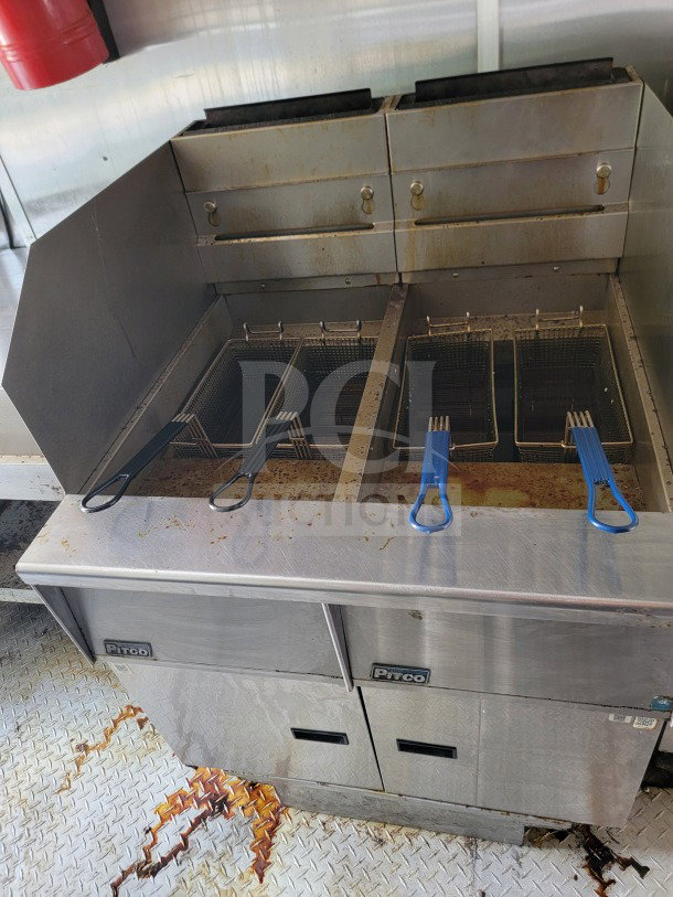 Dual fryer setup with wire baskets on a stainless steel countertop in the 2019 Diamond Cargo mobile kitchen trailer, showing signs of use.