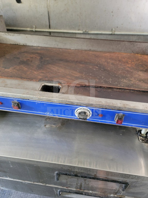 Globe Electric Griddle with visible wear, blue control panel, temperature dial, and switches in mobile kitchen trailer.