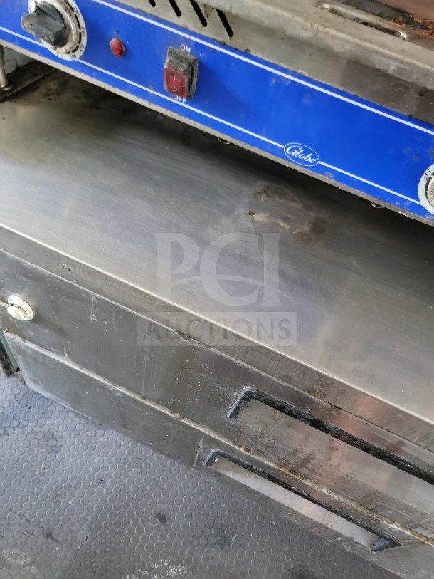 Diamond Cargo trailer interior with Globe griddle. Control knobs visible, slightly worn condition. Part of mobile kitchen setup.