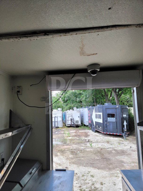 Interior view of 2019 Diamond Cargo mobile kitchen trailer, showing shelving and electrical wiring. Exterior trailers visible outside.