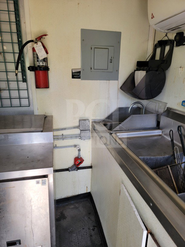 Interior view of 2019 Diamond Cargo kitchen trailer showing sink, fryer, stainless steel surfaces, fire extinguisher, and electrical panel.