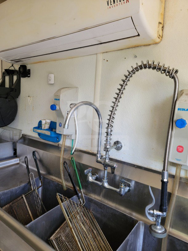 Mobile kitchen trailer sink with commercial faucet and fryer baskets. Ventus inverter and Ecolab dispenser visible above.