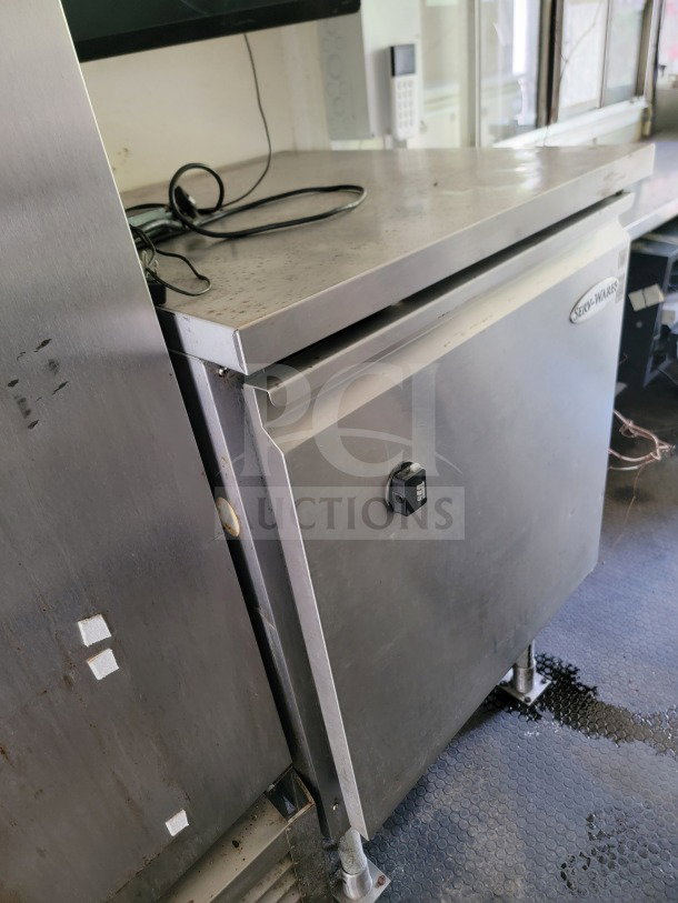 Serv-Ware stainless steel refrigeration unit in mobile commercial kitchen trailer. Minor wear visible.