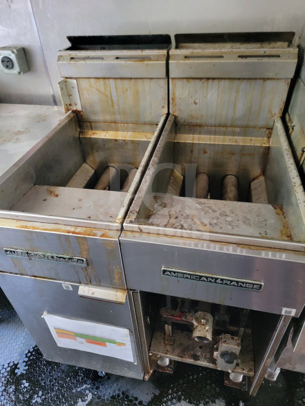 Commercial fryer units inside a Diamond Cargo kitchen trailer, featuring visible signs of rust and wear, branded American Range.