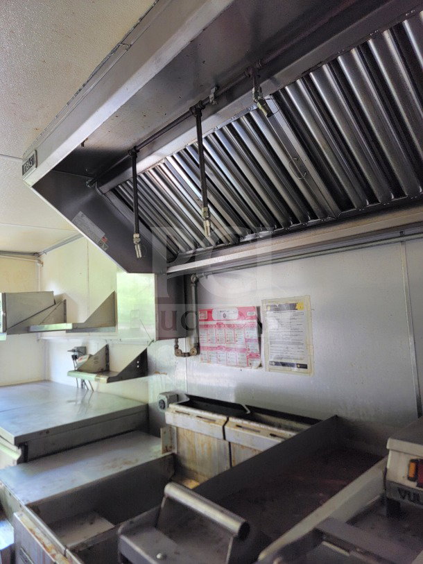 Interior of 2019 Diamond Cargo 24' mobile kitchen trailer with Serv-Ware equipment. Visible ventilation hood, shelves, and cooking area.