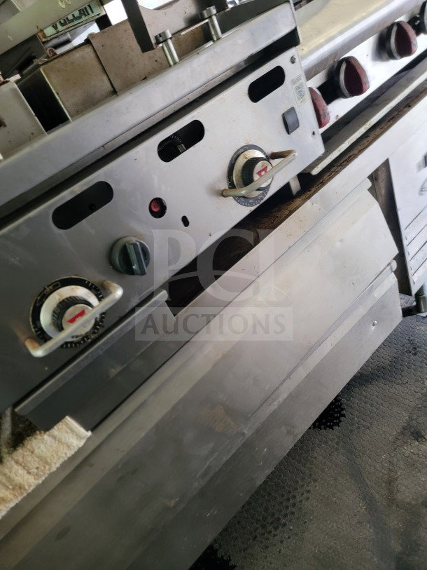 Close-up of commercial kitchen equipment inside Diamond Cargo mobile kitchen trailer, featuring dials and stainless steel surfaces.