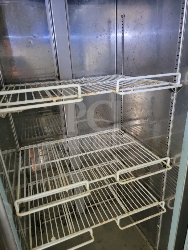 Interior view of refrigerated section in Diamond Cargo Mobile Kitchen Trailer. Features metal shelves and some visible wear.