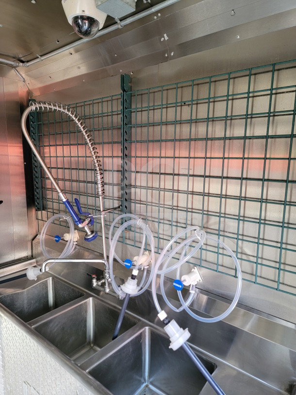 2021 Forest River mobile kitchen trailer interior with sink, hose attachments, and camera. Stainless steel finish, clean and well-maintained.