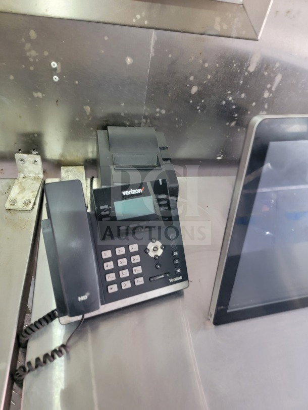 Phone installed in Forest River mobile kitchen trailer. Yealink device on stainless steel surface, for communication use.