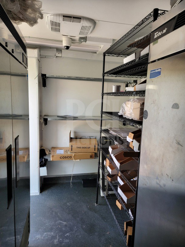 Interior of 2021 SDG 8.5' x 26' trailer with Turbo Air refrigeration, wire shelves, and storage boxes. Clean, equipped setup.