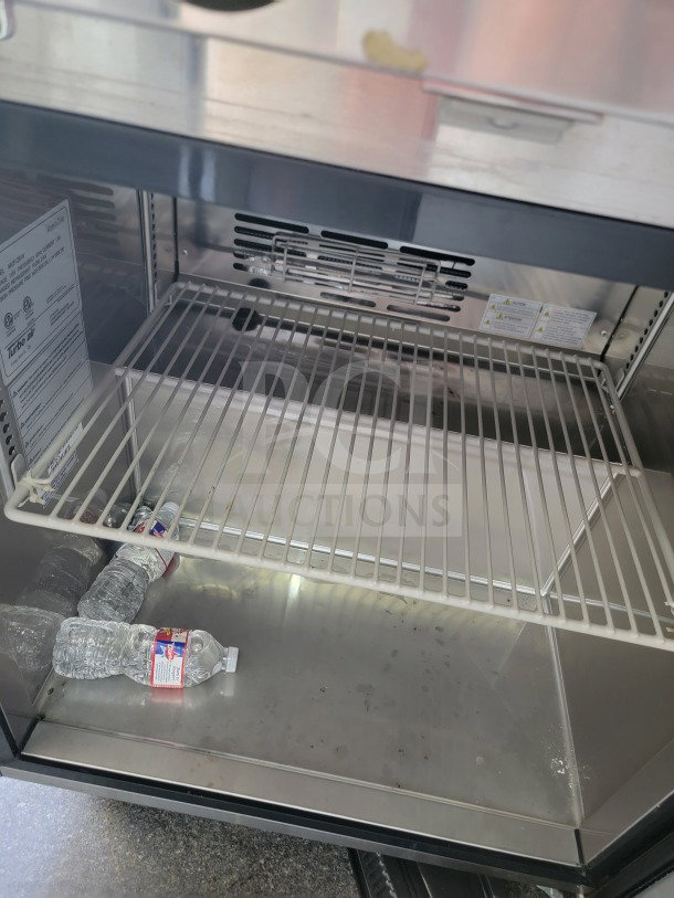 Interior of Turbo Air refrigeration unit inside SDG 2021 8.5' x 26' trailer, showing empty shelf and scattered water bottles.