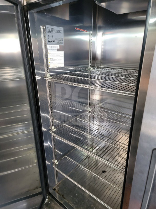 Interior of a Turbo Air refrigerated trailer with wire shelving, stainless steel finish, and visible model label.