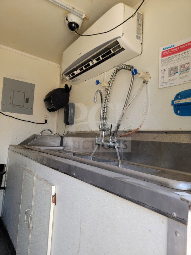 Interior of 2019 Diamond Cargo mobile kitchen trailer with stainless steel sink, faucet, wall-mounted air unit, and Ecolab instructions.