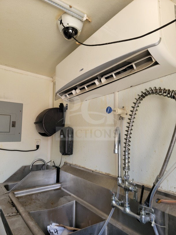Stainless steel sink area inside 2019 Diamond Cargo 8.5' x 24' mobile kitchen trailer, featuring industrial faucet, wall-mounted HVAC unit, and camera.
