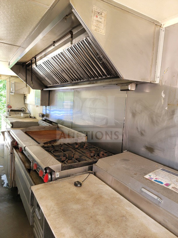 Inside view of a 2019 Diamond Cargo 8.5' x 24' mobile kitchen trailer, featuring an American Range cooking suite.