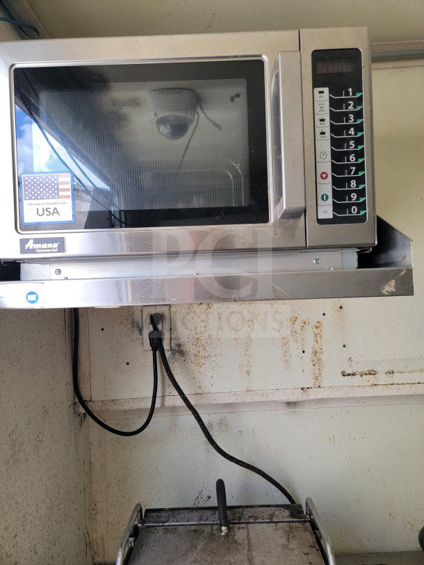 Amana Commercial microwave in mobile kitchen trailer, stainless finish, keypad visible. Shows U.S. fabrication sticker.