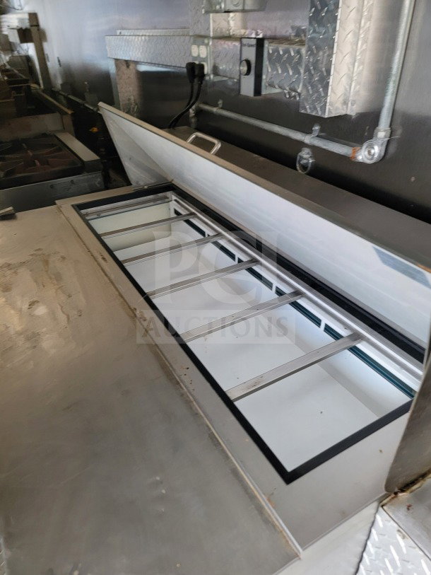 2021 BT&S mobile kitchen trailer interior, featuring open stainless steel storage compartment and diamond plate accents.