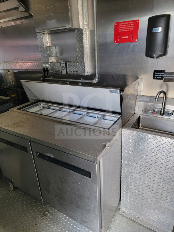 2021 BT&S 8.5x24 tandem-axle mobile kitchen trailer interior. Features stainless steel prep counter, sink, and glove dispenser.