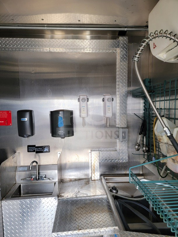 2021 BT&S 8.5' x 24' mobile kitchen trailer interior with stainless steel sink, soap dispensers, and wire shelving.