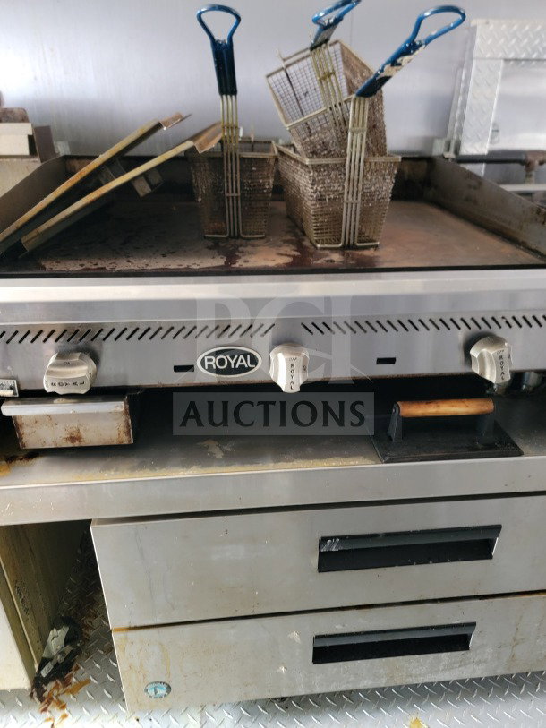 Industrial kitchen equipment inside mobile trailer, featuring Royal brand fryer baskets and griddle, showing signs of use.