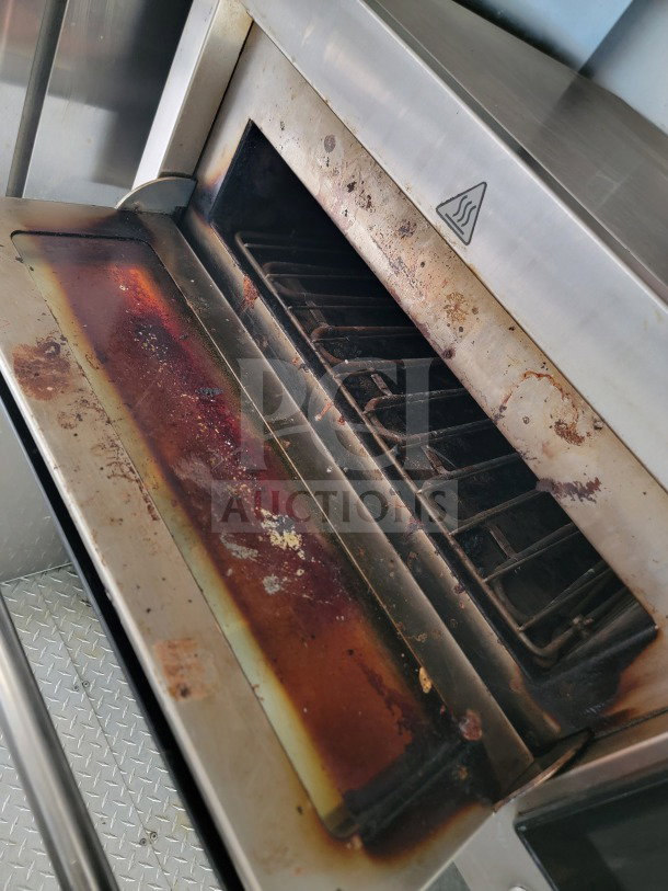 Interior view of a mobile kitchen oven in a 2021 BT&S trailer, showing signs of use with rust and discoloration on the metal surfaces.