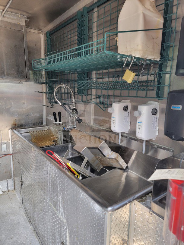 2021 Titanium Cargo 8.5' x 24' mobile kitchen interior, featuring diamond plate surfaces, storage racks, and cleaning area.