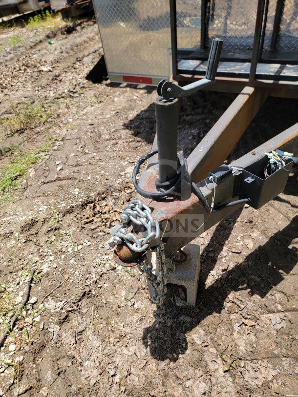 Tandem-axle mobile kitchen trailer hitch with chains, resting on a cinder block. Diamond plate front visible, ready for towing.