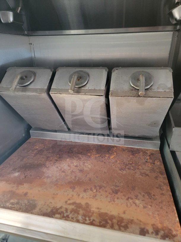 Three stainless steel fry baskets inside a 2021 Titanium Cargo 8.5' x 24' mobile kitchen trailer, showing signs of wear.
