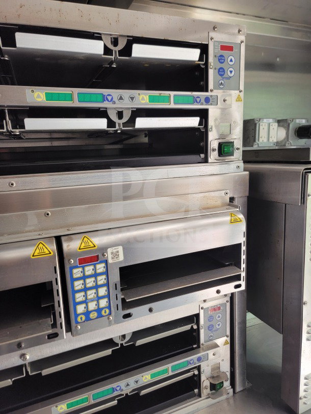 Control panel of kitchen equipment inside a 2021 Titanium Cargo 8.5' x 24' mobile kitchen trailer, featuring digital displays and warning labels.