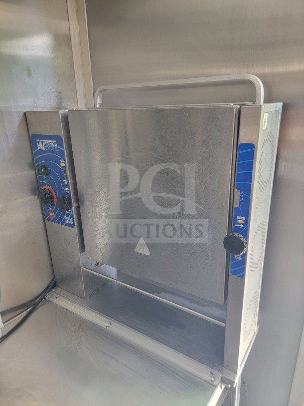 Prince Castle kitchen equipment in stainless steel, mounted in a mobile kitchen trailer. Features control dials and safety warning label.