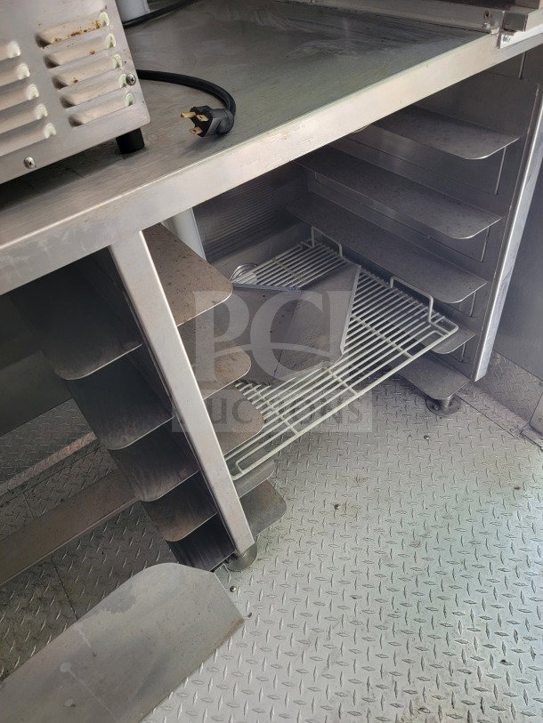 Interior of 2021 Titanium Cargo Mobile Kitchen Trailer showing stainless steel shelving and diamond plate flooring.