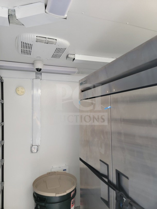 Interior view of 2021 SDG 8.5' x 26' mobile kitchen trailer, featuring True refrigeration unit and overhead lighting.