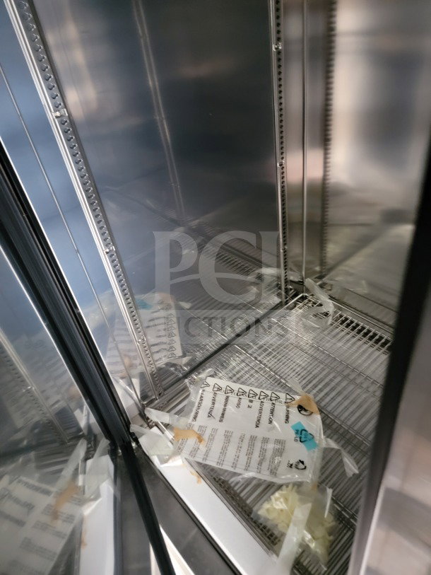 Interior view of a mobile kitchen trailer's stainless steel rack with safety instruction tags visible.