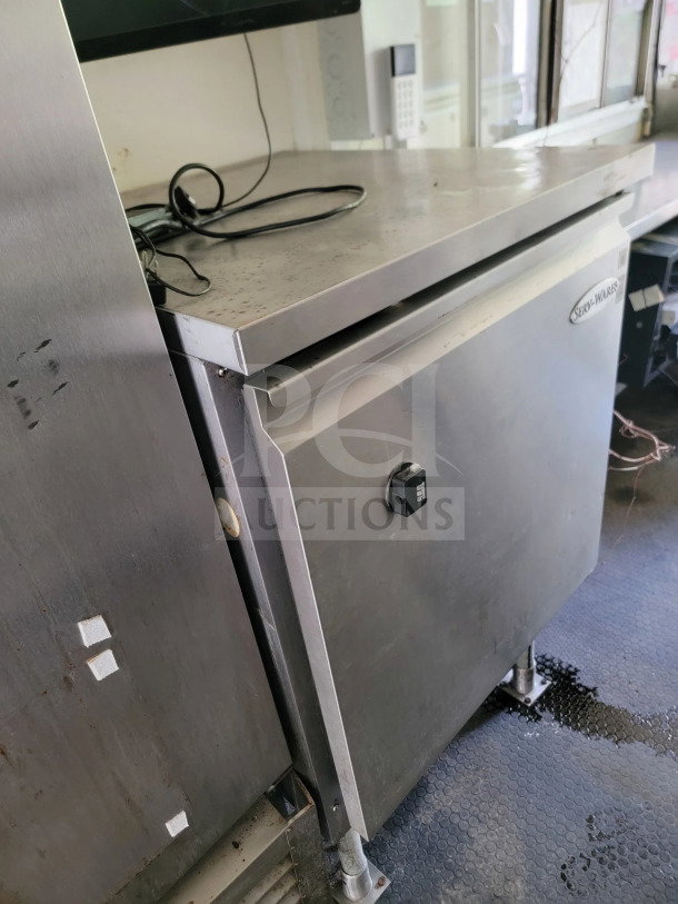 Mobile kitchen trailer interior showcasing a Serv-Ware refrigeration unit. Stainless steel finish with visible wear.