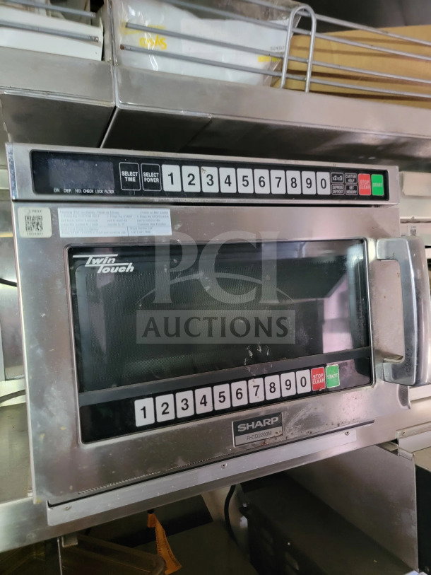 Sharp R-CD2200M Twin Touch commercial microwave with numeric keypad, visible wear, and stainless steel exterior.