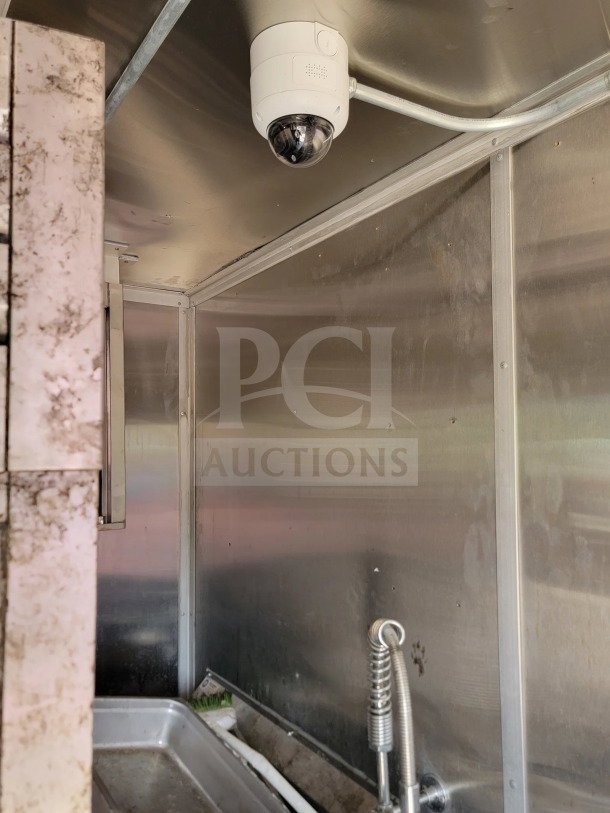Interior of 2021 Rock Solid Cargo mobile kitchen trailer, stainless steel walls, sink with hose, security camera installed.