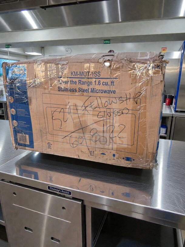 Box of KoolMore KM-MOT-1SS microwave, never used, 1.6 cu. ft., stainless steel, UL listed, with labeling and markings visible.