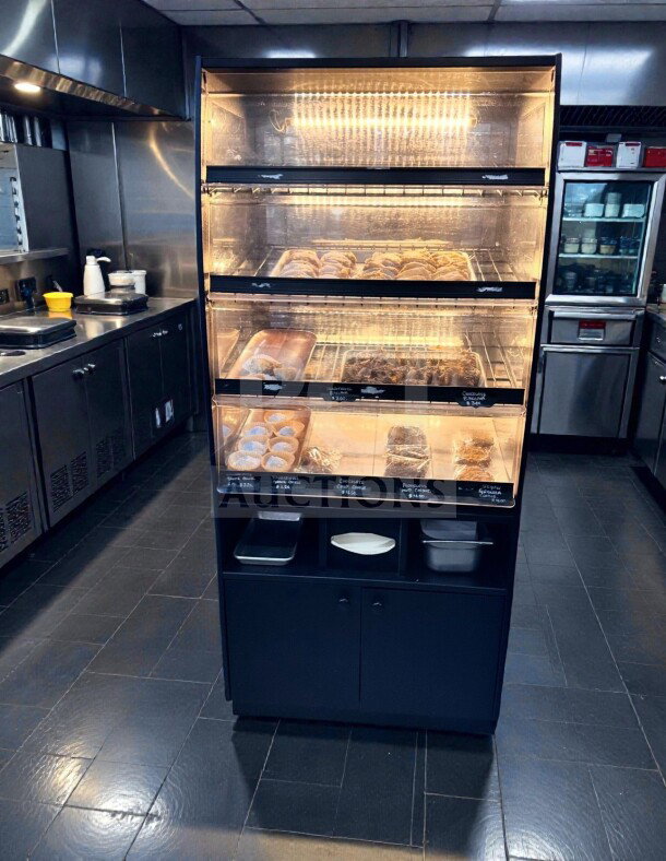 Illuminated black 3-level dry display case for bakery items, in immaculate condition, fully inspected and operational.