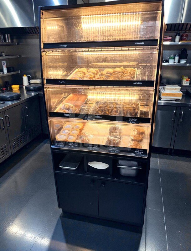 Illuminated black finish bakery display case, three levels, non-refrigerated, immaculate condition, fully operational.