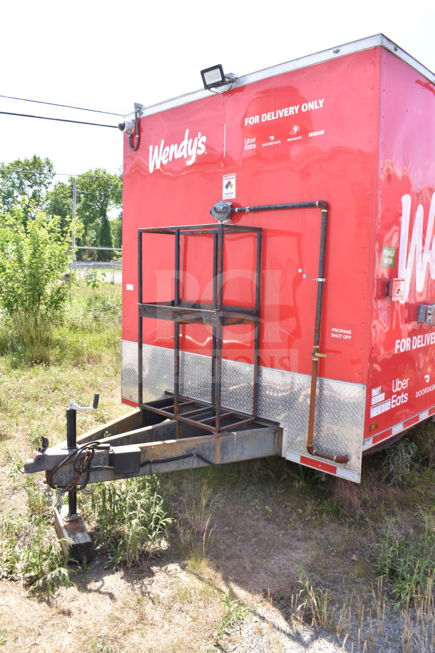 Red Wendy's food trailer with delivery logos and propane hookup. Visible "Propane Shut Off" and "Portable Water" labels.
