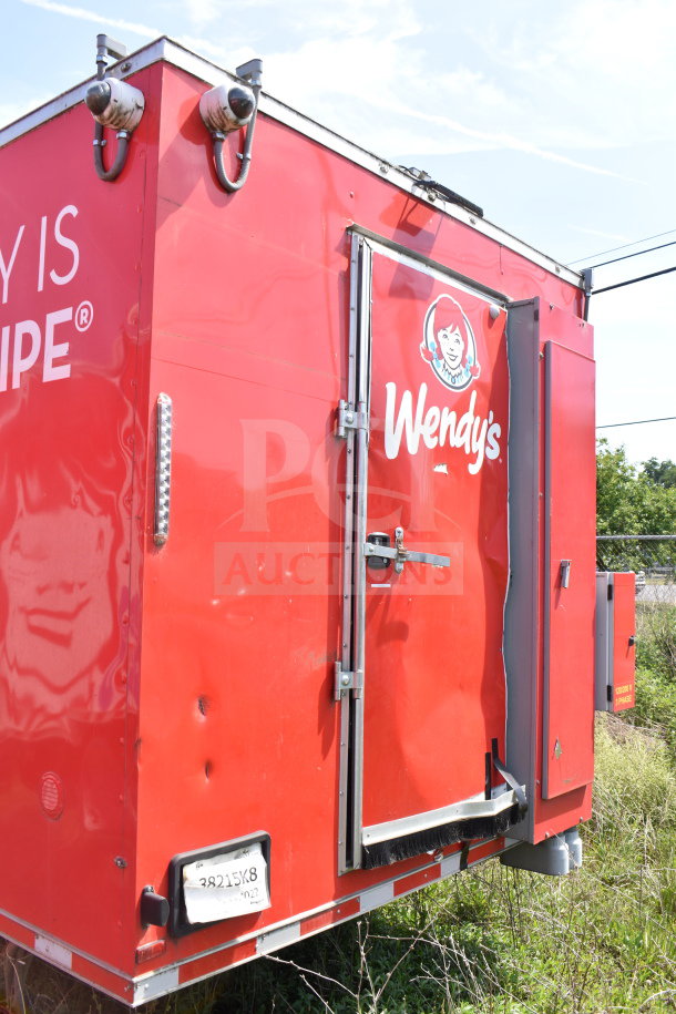 Wendy's red food trailer with logo, visible door handle, dents, and license plate "38215X8". Outdoor setting.