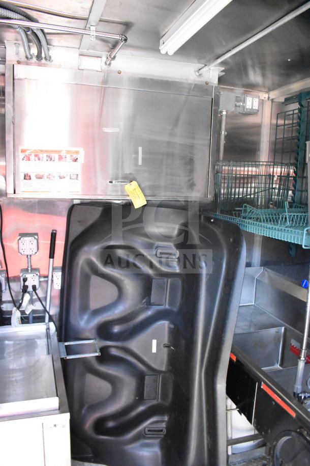 Interior of Wendy's food trailer showing stainless steel equipment, electrical outlets, and storage racks; yellow tag present.
