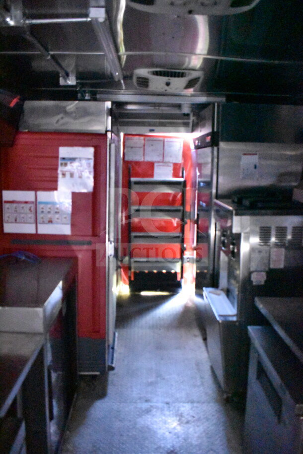 Interior of Wendy's food trailer, featuring stainless steel appliances, red paneling, and posted service guidelines.