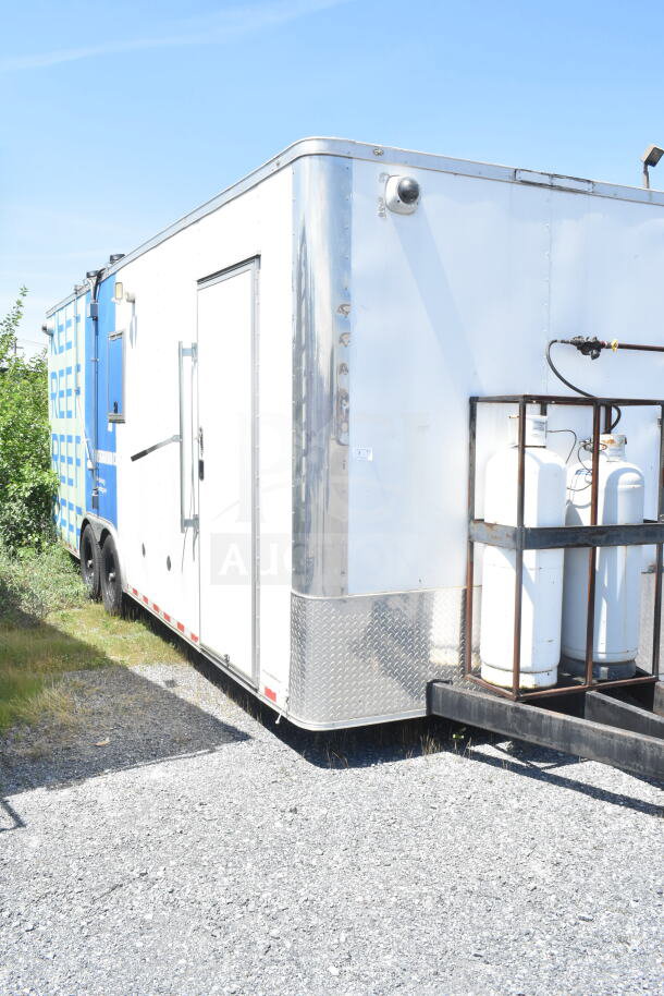 Diamond Cargo 8.5'x24' food trailer, white exterior, dual axles, propane tanks mounted at front, good condition.
