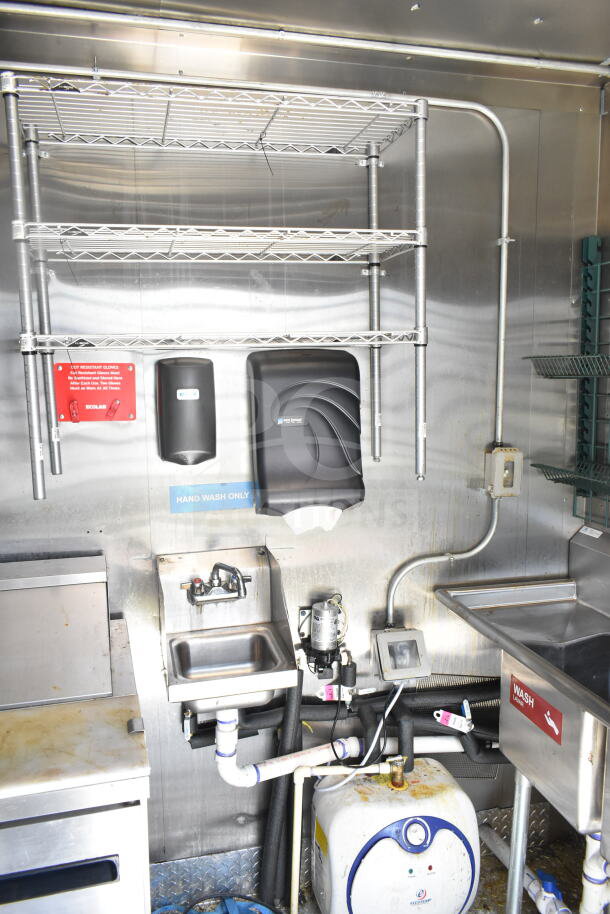 Diamond Cargo 8.5'x24' food trailer interior with metal shelves, hand wash sink, soap and towel dispensers, and water heater.